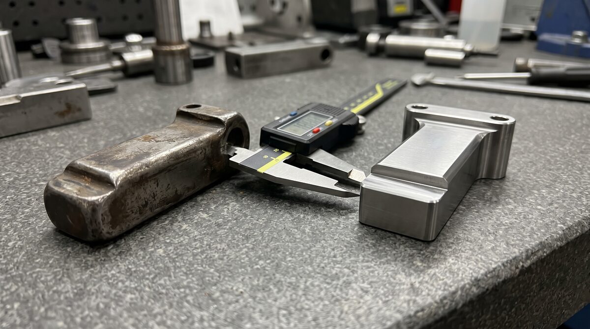 Close detail of a reverse-engineered part beside its worn original on a measurement bench, calipers between them, cool light